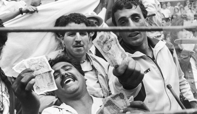 Image showing Algerian fans waving money in protest of the collusion taking place during The Disgrace of Gijón